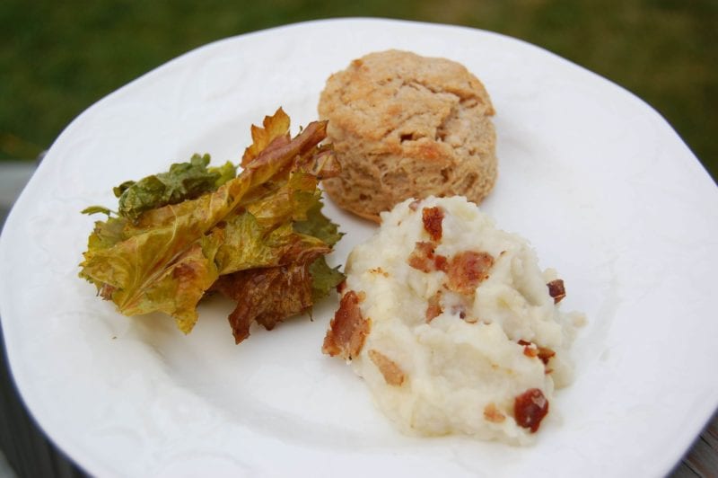 Kale chips, mashed potatoes, and whole-wheat biscuit on a plate. 