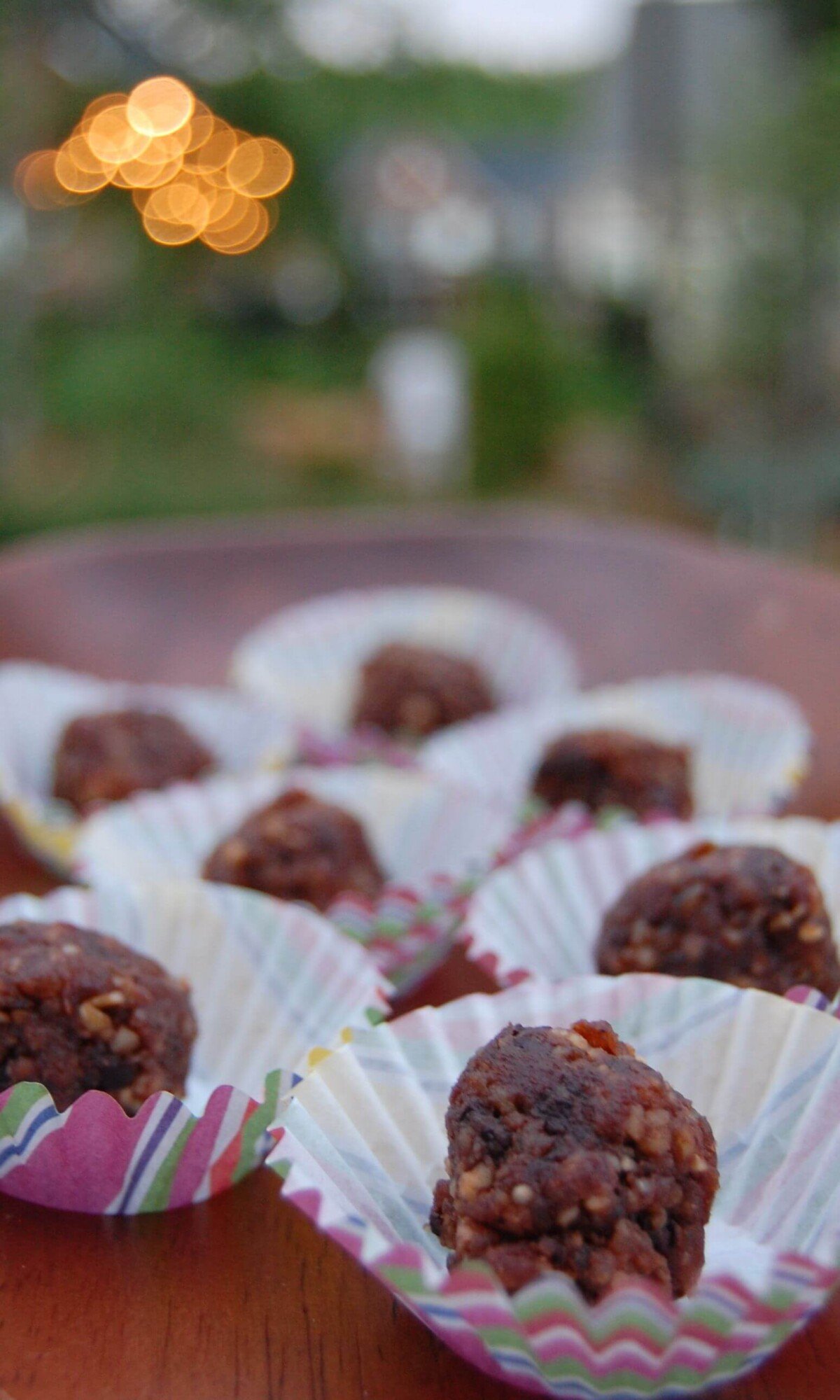 Six homemade chocolate peanut butter power balls in decorative muffin cups.