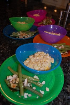 Plates of homemade macaroni and cheese and greenbeans. 