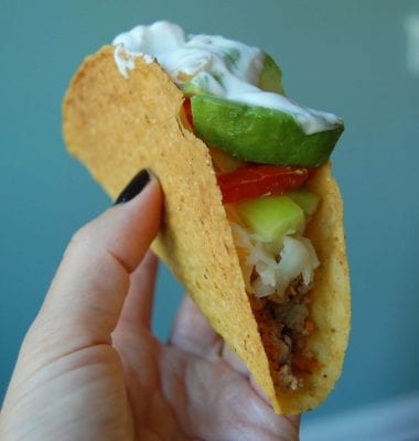 Hard shell turkey taco topped with cheese, bell peppers, tomatoes avocado, and sour cream. 