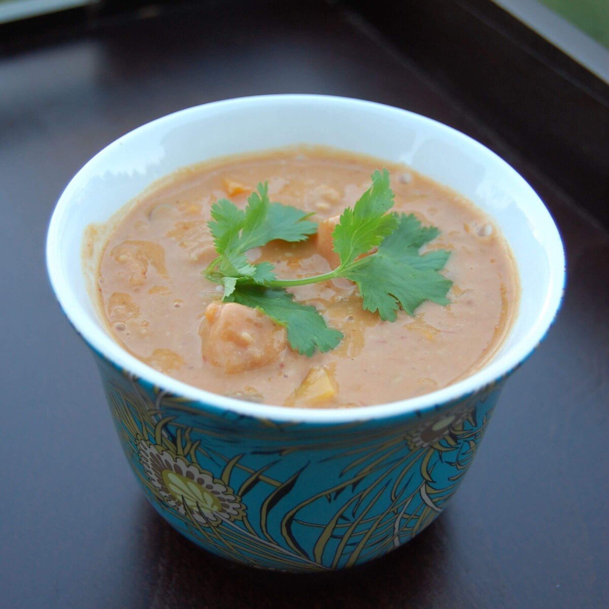 Peanut Squash Soup in a decorative bowl topped with cilantro. 