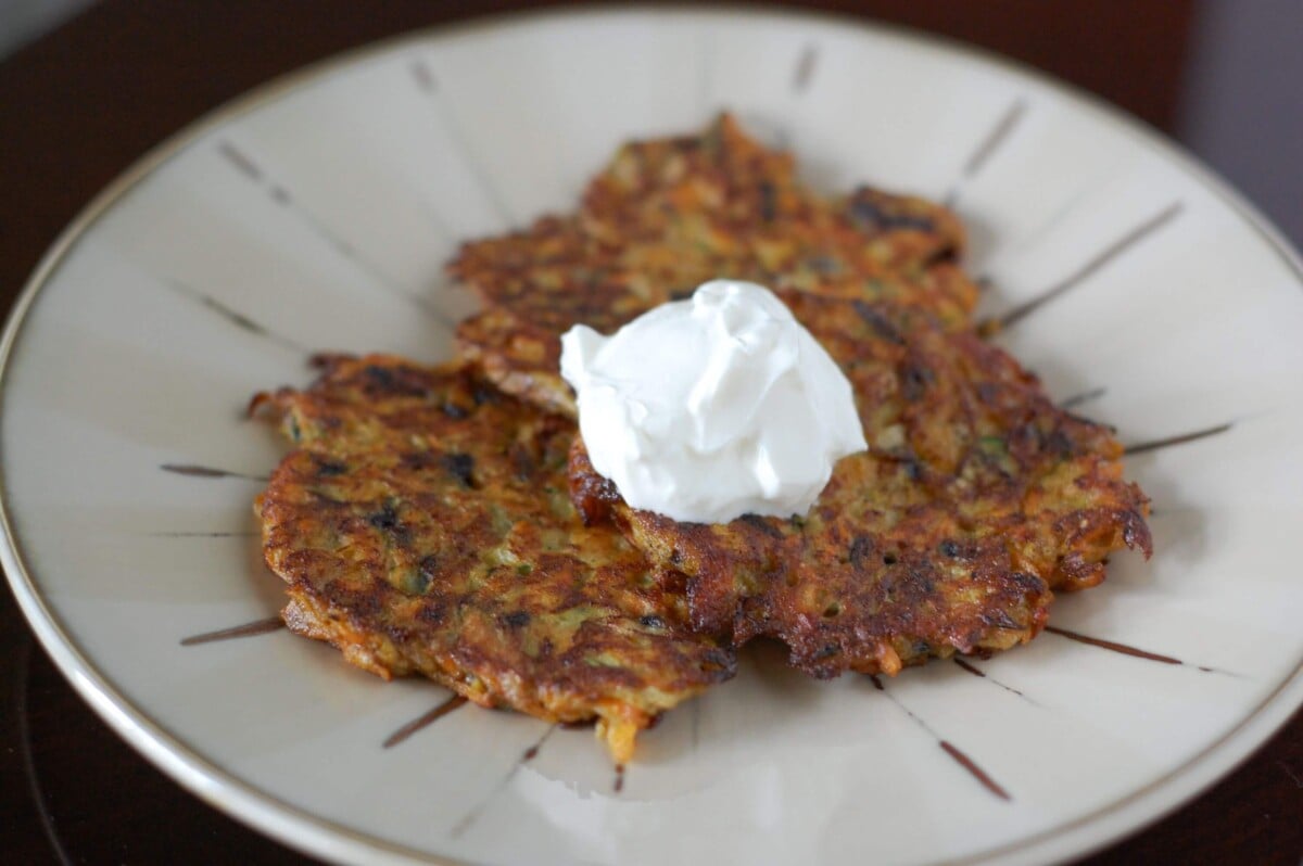 Three homemade vegetable pancakes topped with a dollup of sour cream. 