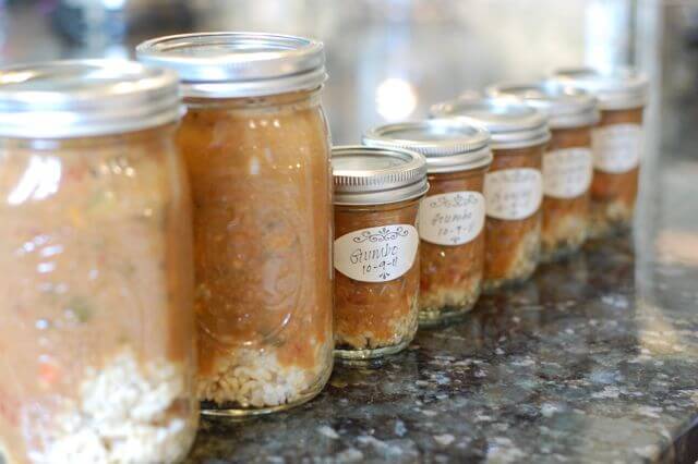 Seven jars of homemade soups ready to go in the freezer. 