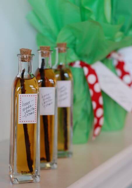 Three glass bottles with homemade vanilla extract in them with a decorated label. 