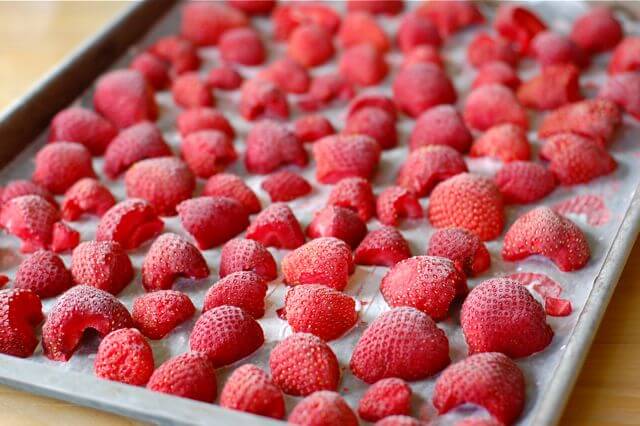 Sheet pan of frozen strawberry halves.