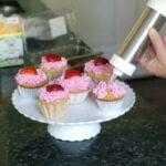 finve vanilla cupcakes on a stand with strawberry frosting on top