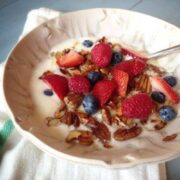 Bowl of yogurt topped with fresh berries and granola.