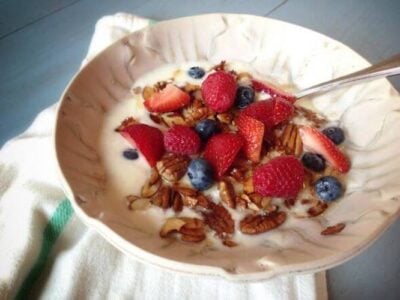 Bowl of yogurt topped with fresh berries and granola.