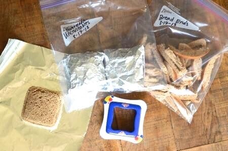 Homemade Uncrustable sandwiches on a table along with a bag of bread ends in a ziplock bag. 
