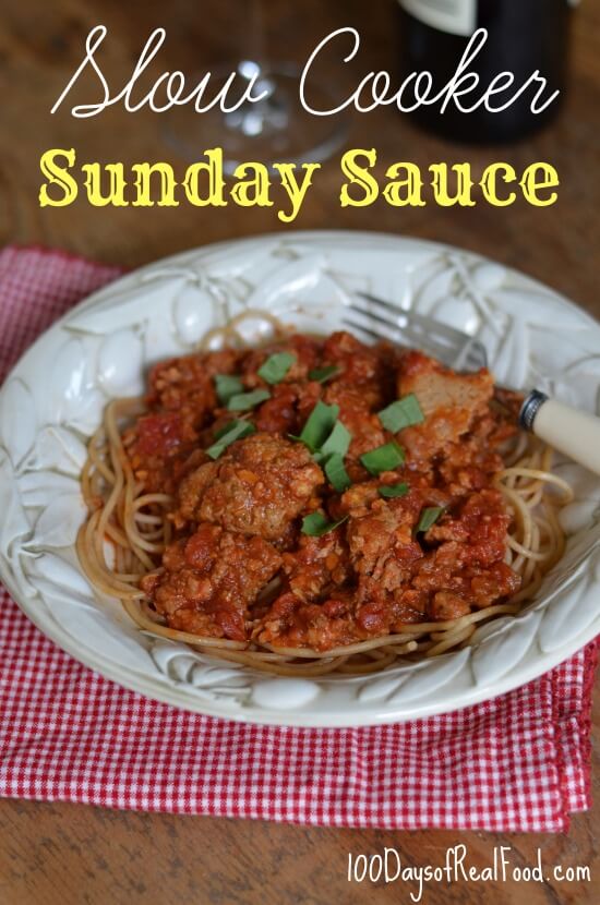 A large bowl of spaghetti topped with Slow Cooker Sunday Sauce and fresh basil.