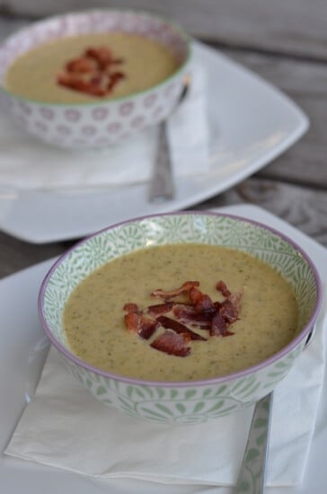 Broccoli Cheese Soup in two decorative bowls topped with bacon pieces.