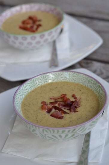 Broccoli Cheese Soup in two decorative bowls topped with bacon pieces. 