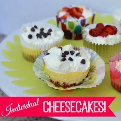 Four mini cheesecakes topped with whipped cream and chocolate chips.