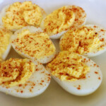 Deviled eggs on a plate topped with paprika.