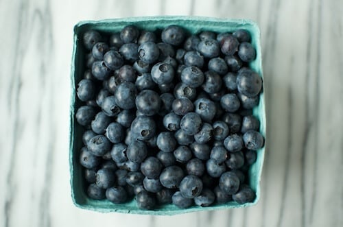 Fresh blueberries in a green carton.