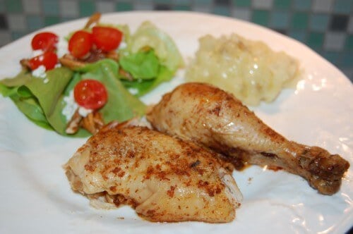 Two pieces of chicken on a dinner plate with a side salad.