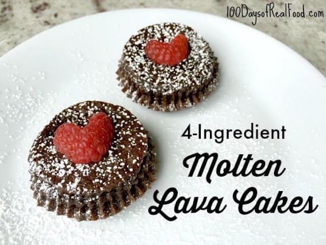 Two molten lava cakes with raspberry hears sprinkled with powdered sugar.