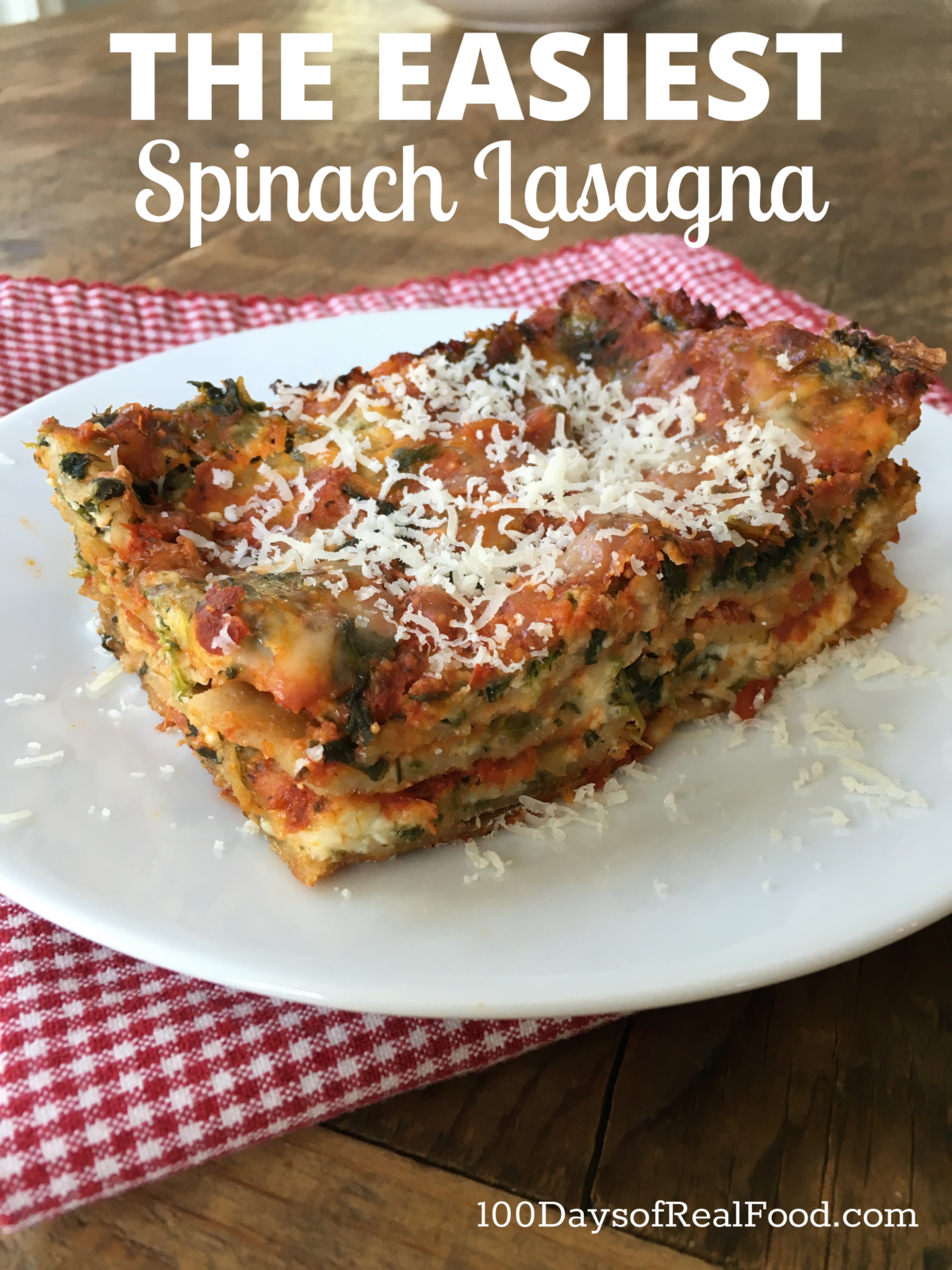 A large piece of spinach lasagna topped with grated cheese on a plate. 