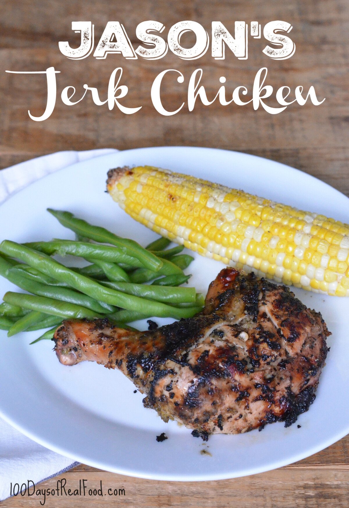 A white dinner plate with grilled jerk chicken leg, green beans, and an ear of corn.