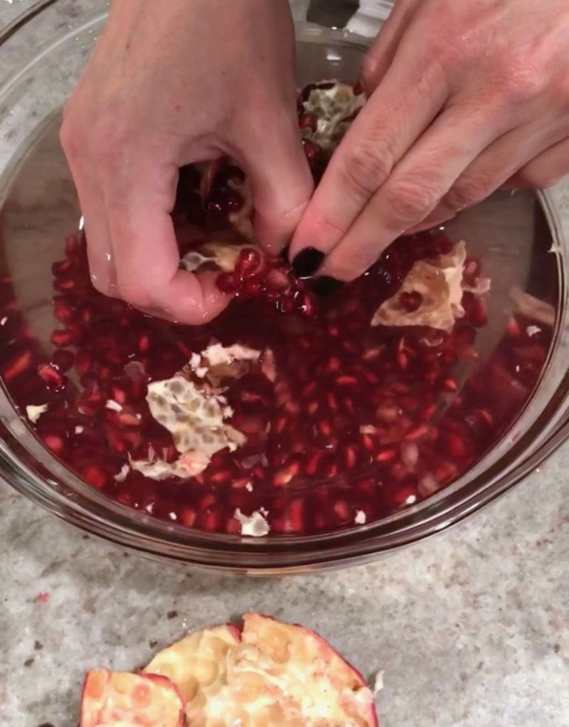Extracting pomegranate seeds in a bowl of water