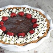 Chocolate pudding pie with raspberries, whipped cream and chocolate sprinkles.