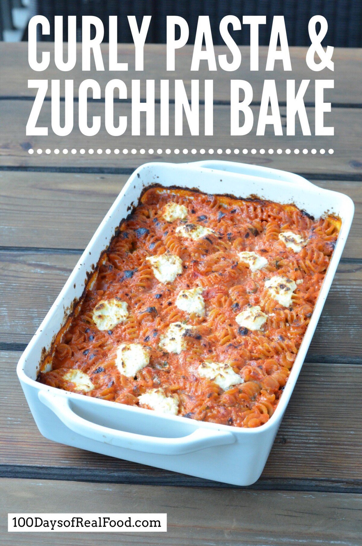 White baking dish loaded with curly pasta in a tomato sauce topped with dollops of ricotta cheese that just came out of the oven. 