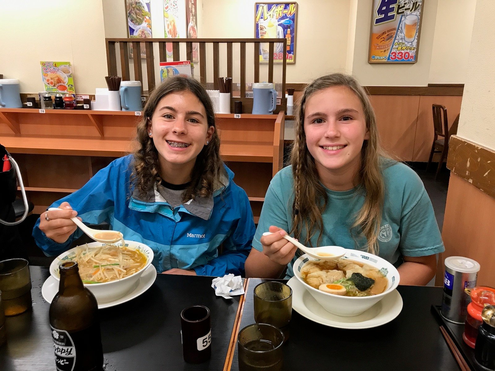 Two young sisters enjoying authentic ramen in a Japanese restaurant in Japan.