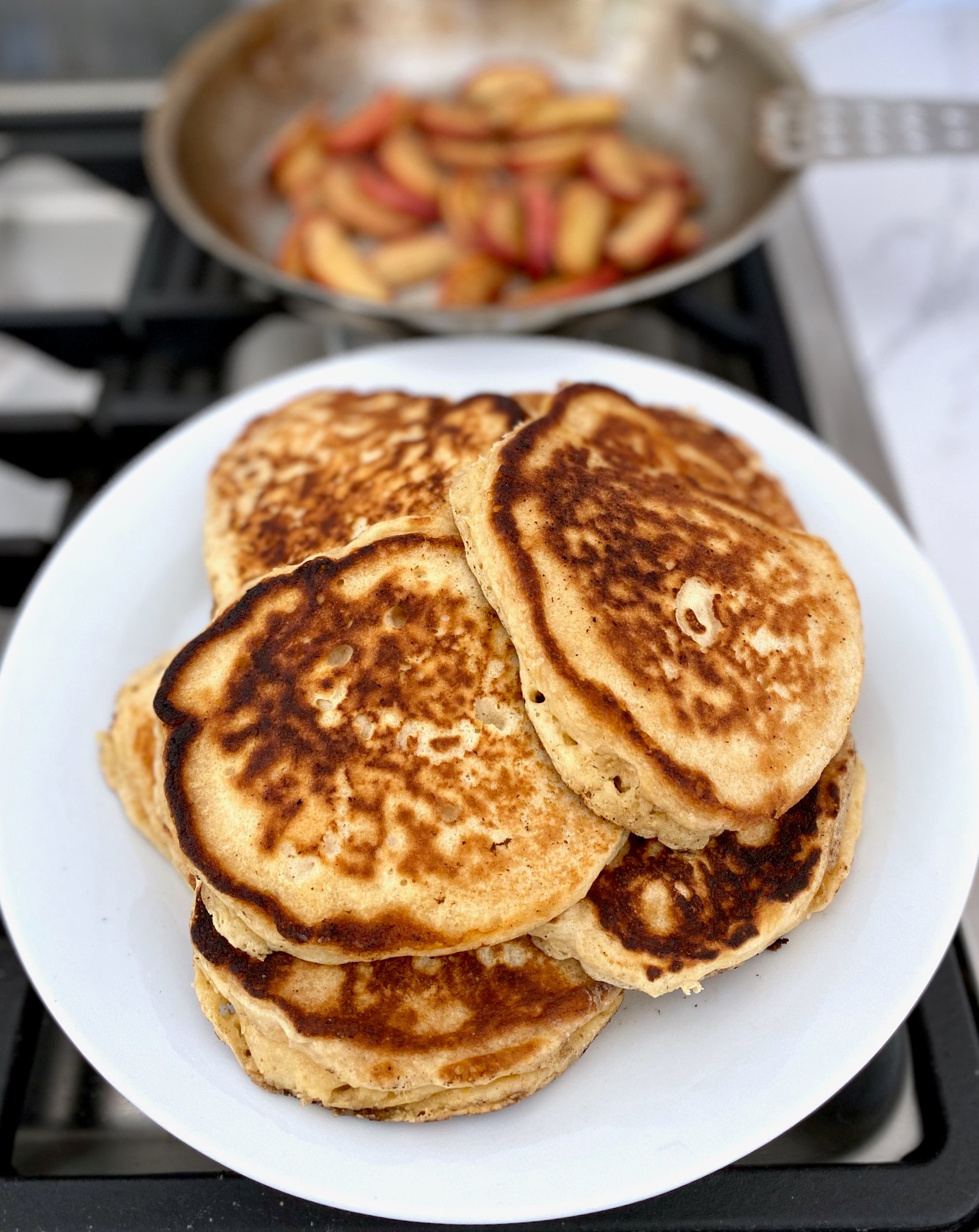 A stack of fluffy Buttermilk Pancakes on a white plate.