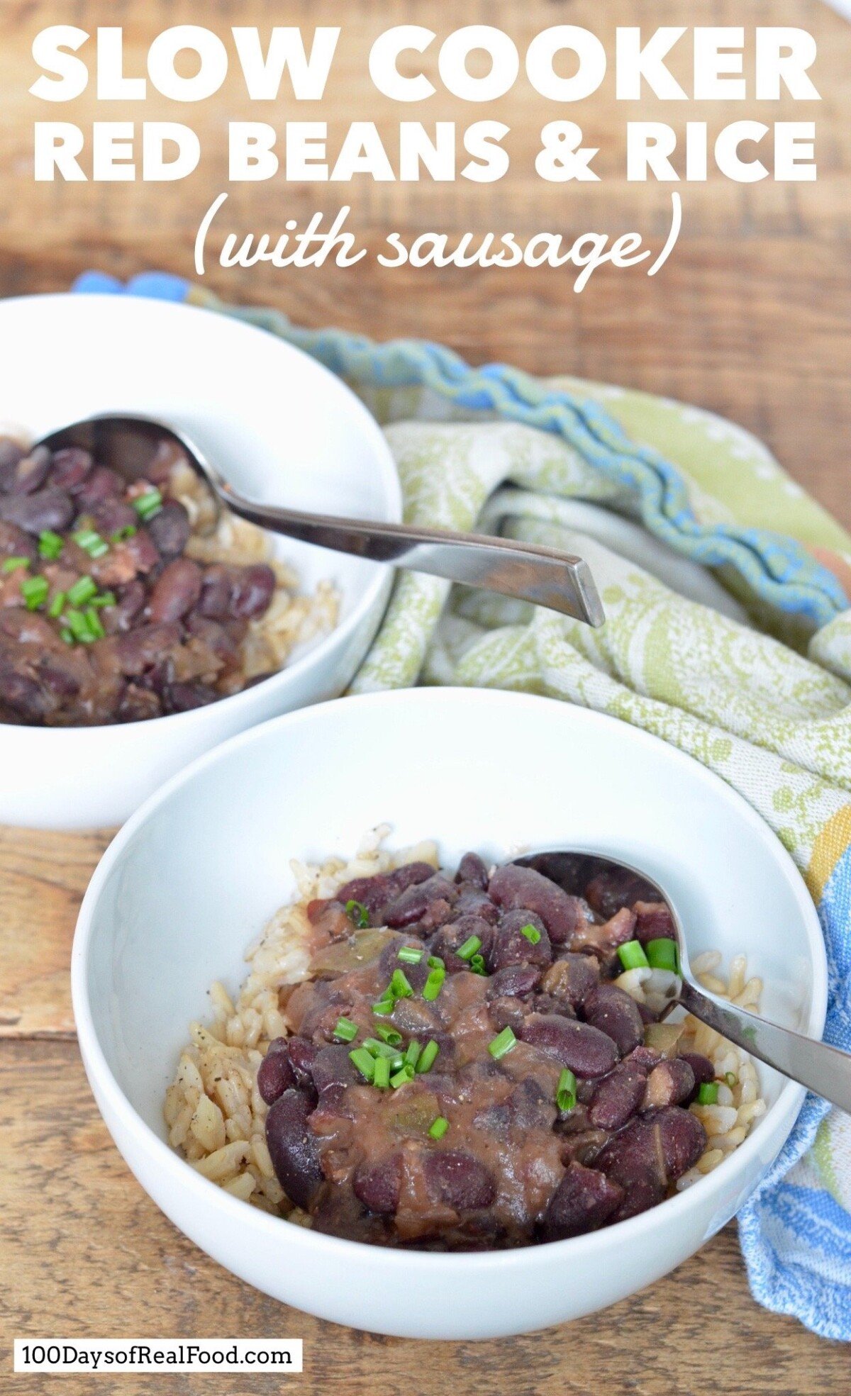 Two bowls and spoons filled with rice and red beans with sausage topped with chopped chives. 