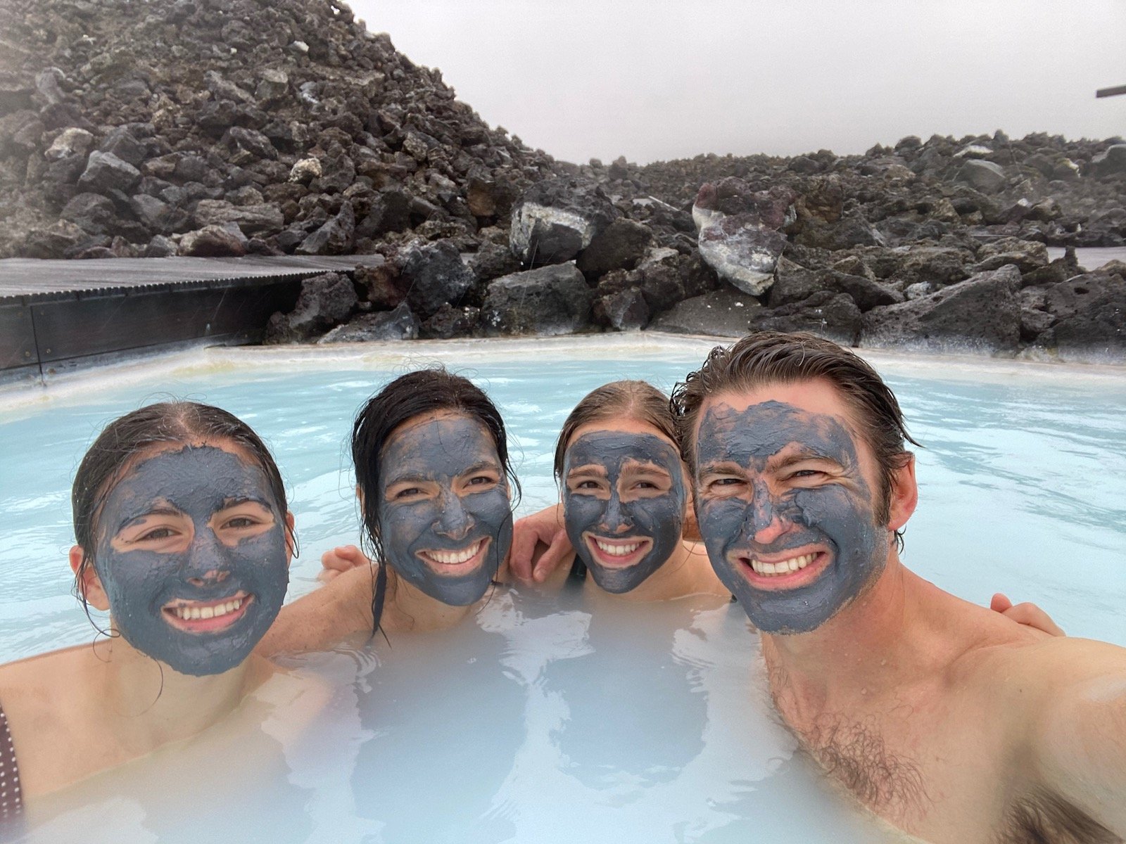 Family posing with mud masks on in the Blue Lagoon in Iceland. 