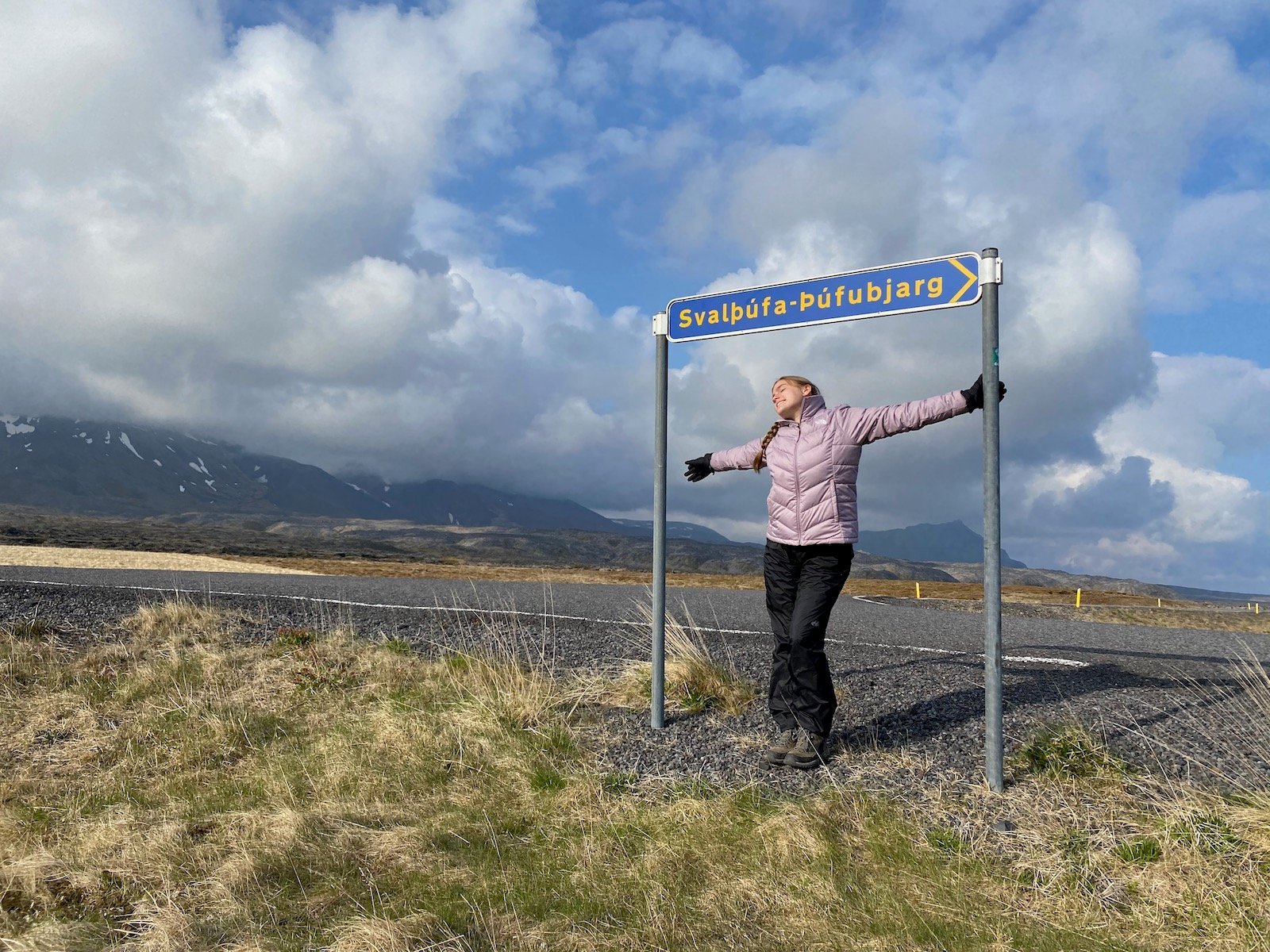 Teen girl posing under sign of Snæfellsjökull National Park.