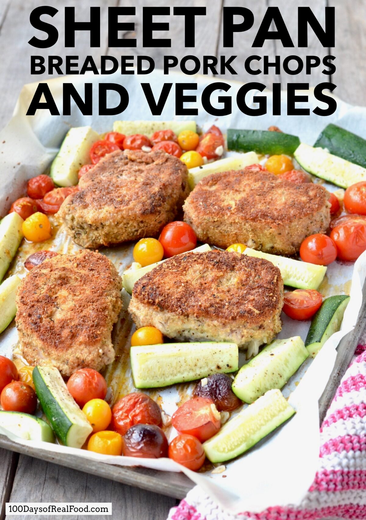 Breaded pork chops with zucchini and grape tomatoes on a baking sheet.