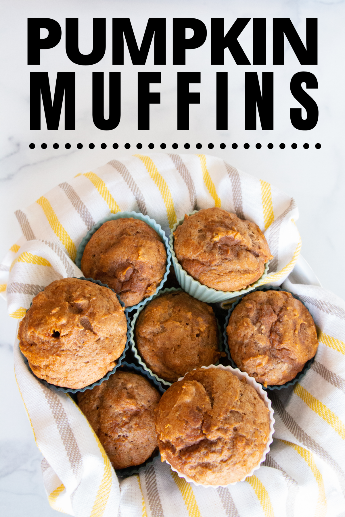 Basket with brown, white, and yellow striped towel holding seven homemade pumpkin muffins.