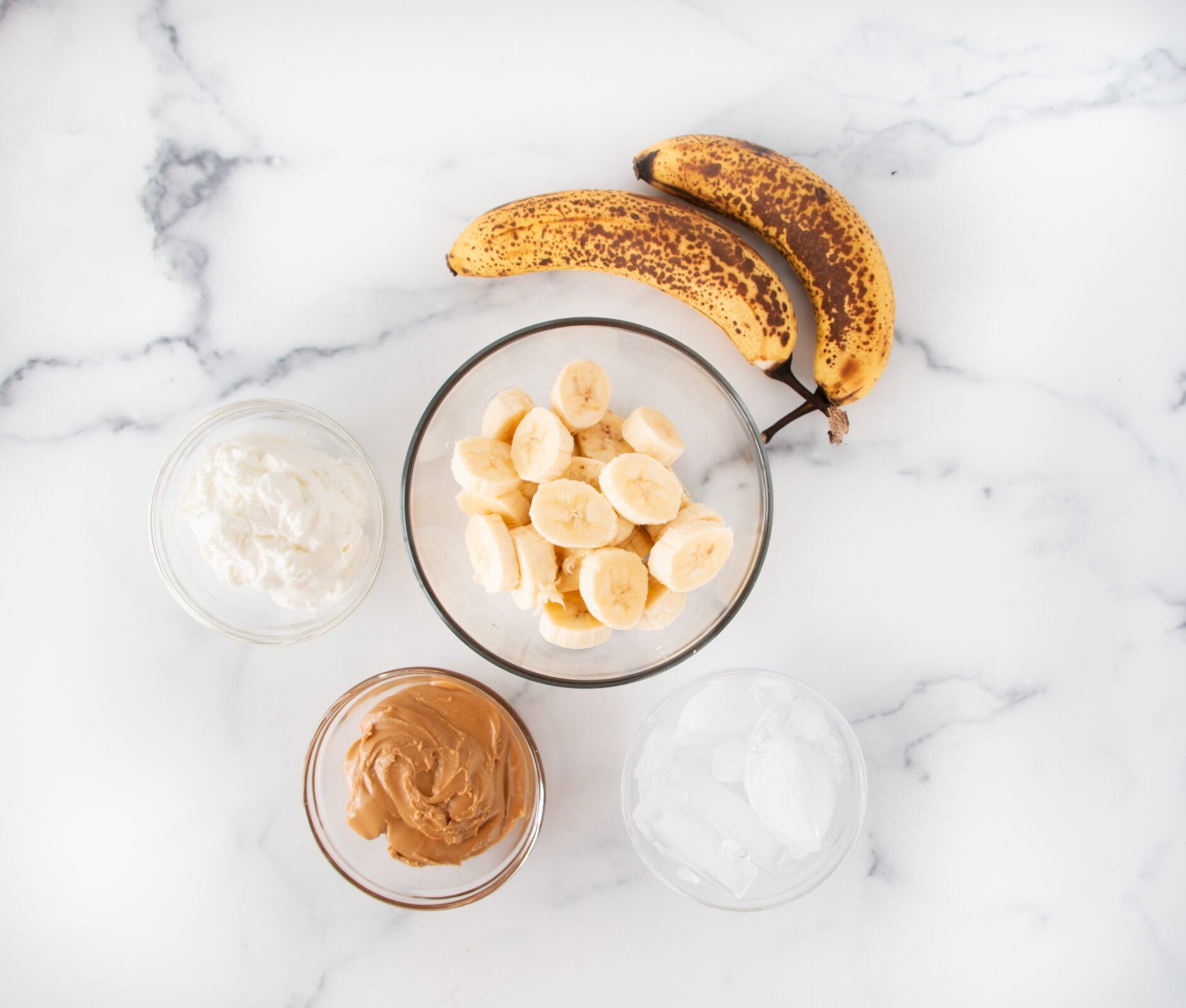 Bananas, yogurt, peanut butter, and ice ready to make a smoothie.