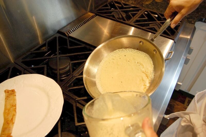 Swirling whole wheat crepe batter in a frying pan to create a thin layer