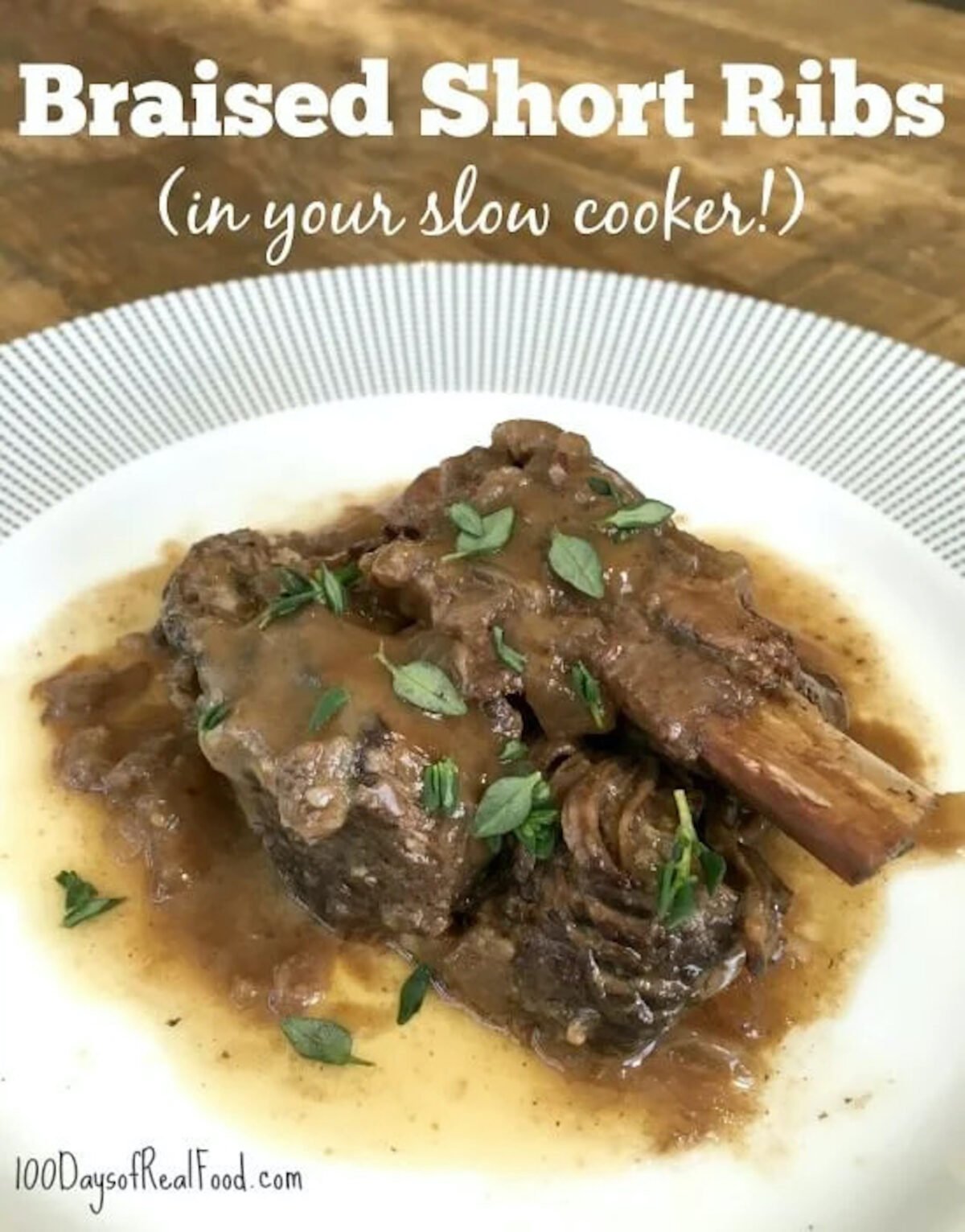 Two meaty braised short ribs on a plate with gravy drizzled over the top with thyme leaves sprinkled on top.