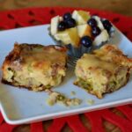 Two pieces of homemade Holiday Breakfast Bake with a side of fresh fruit.