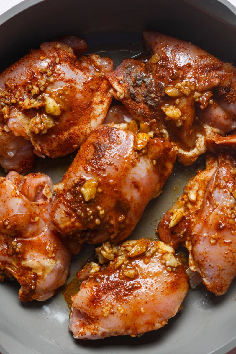 Skillet with seasoned thighs.