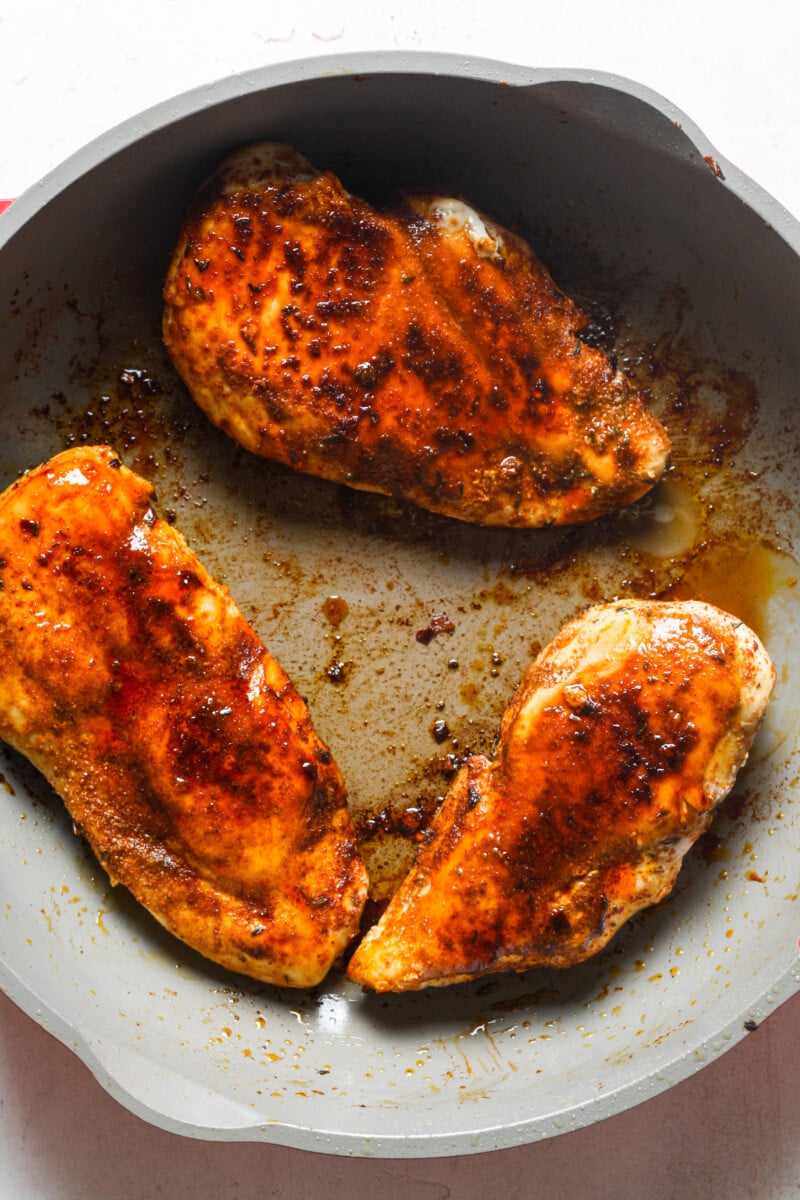 Seasoned breasts in skillet.