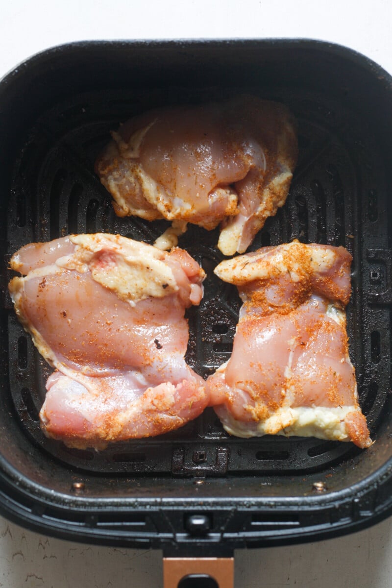 Air fryer basket with chicken thighs.