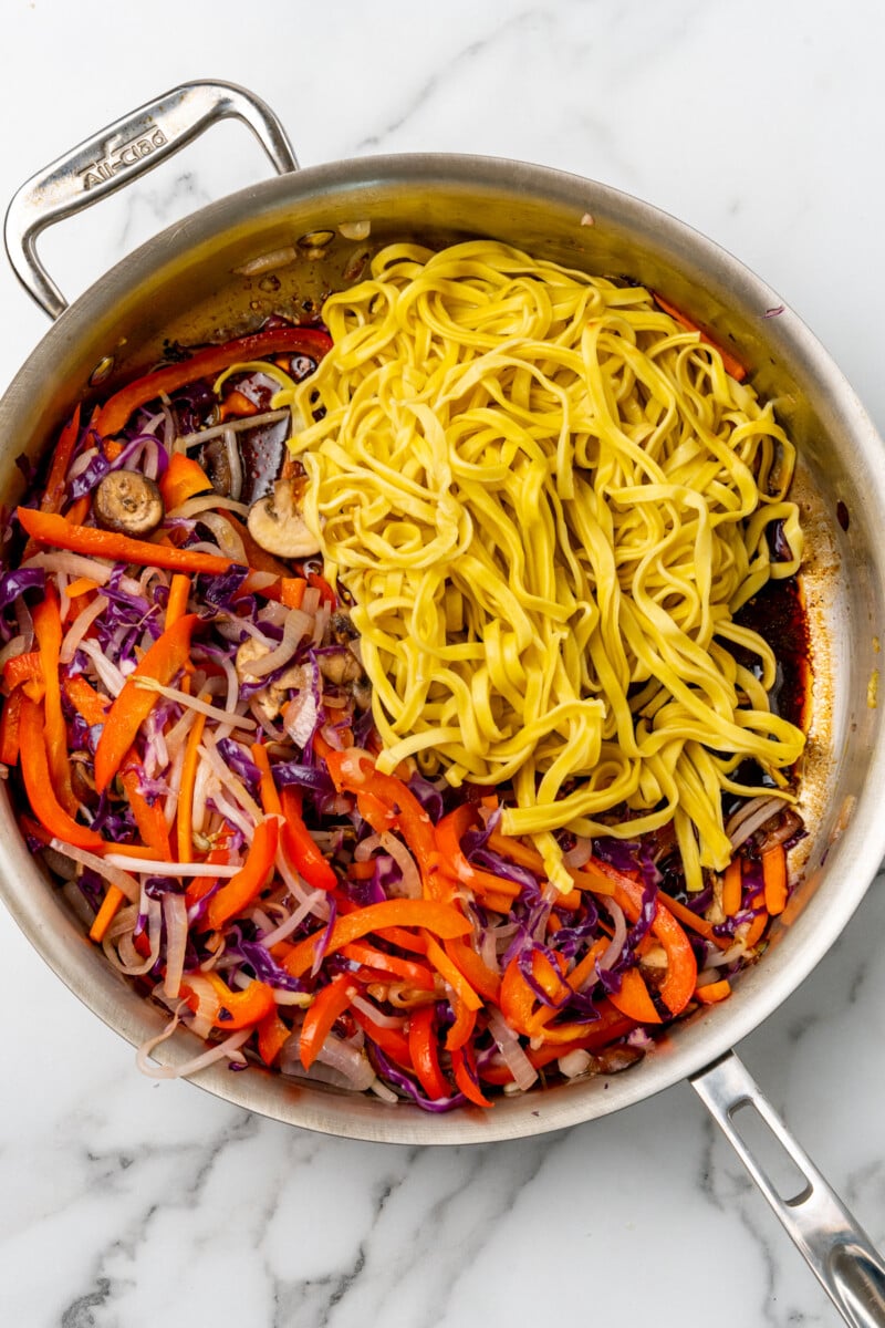 Noodles with veggies in skillet.