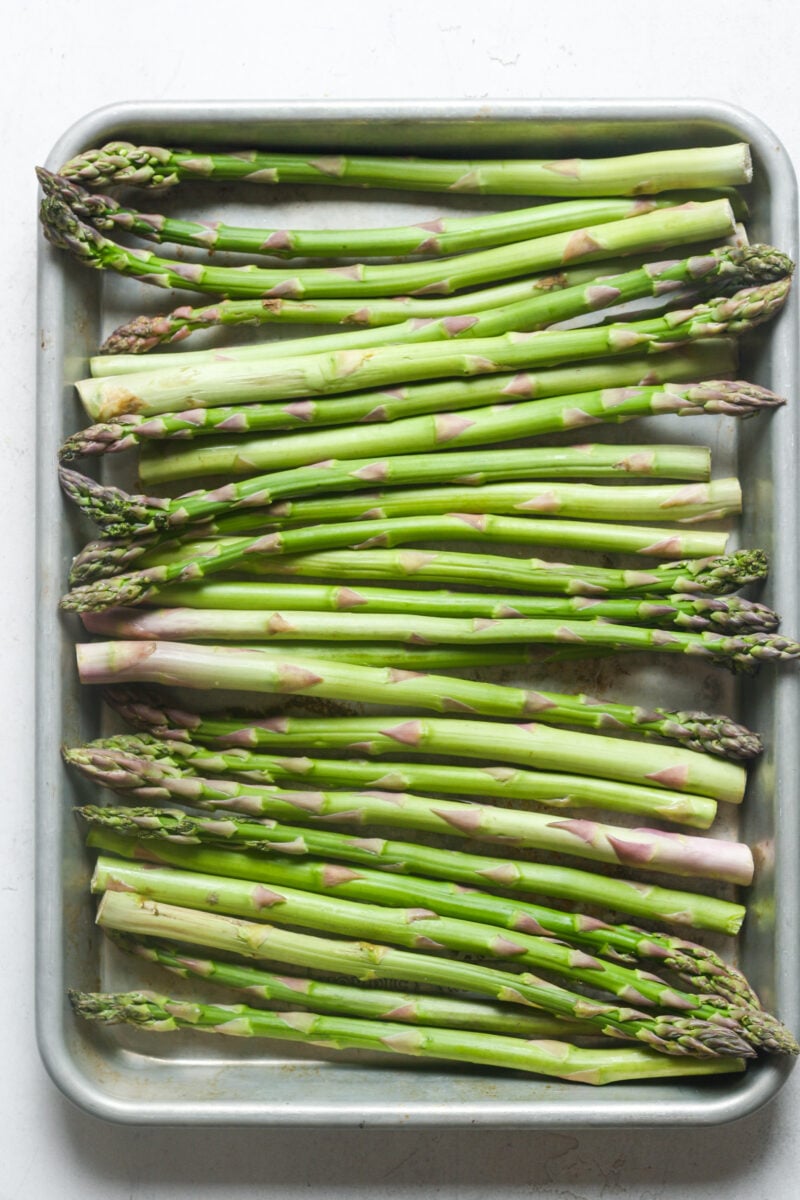 Raw asparagus on pan.