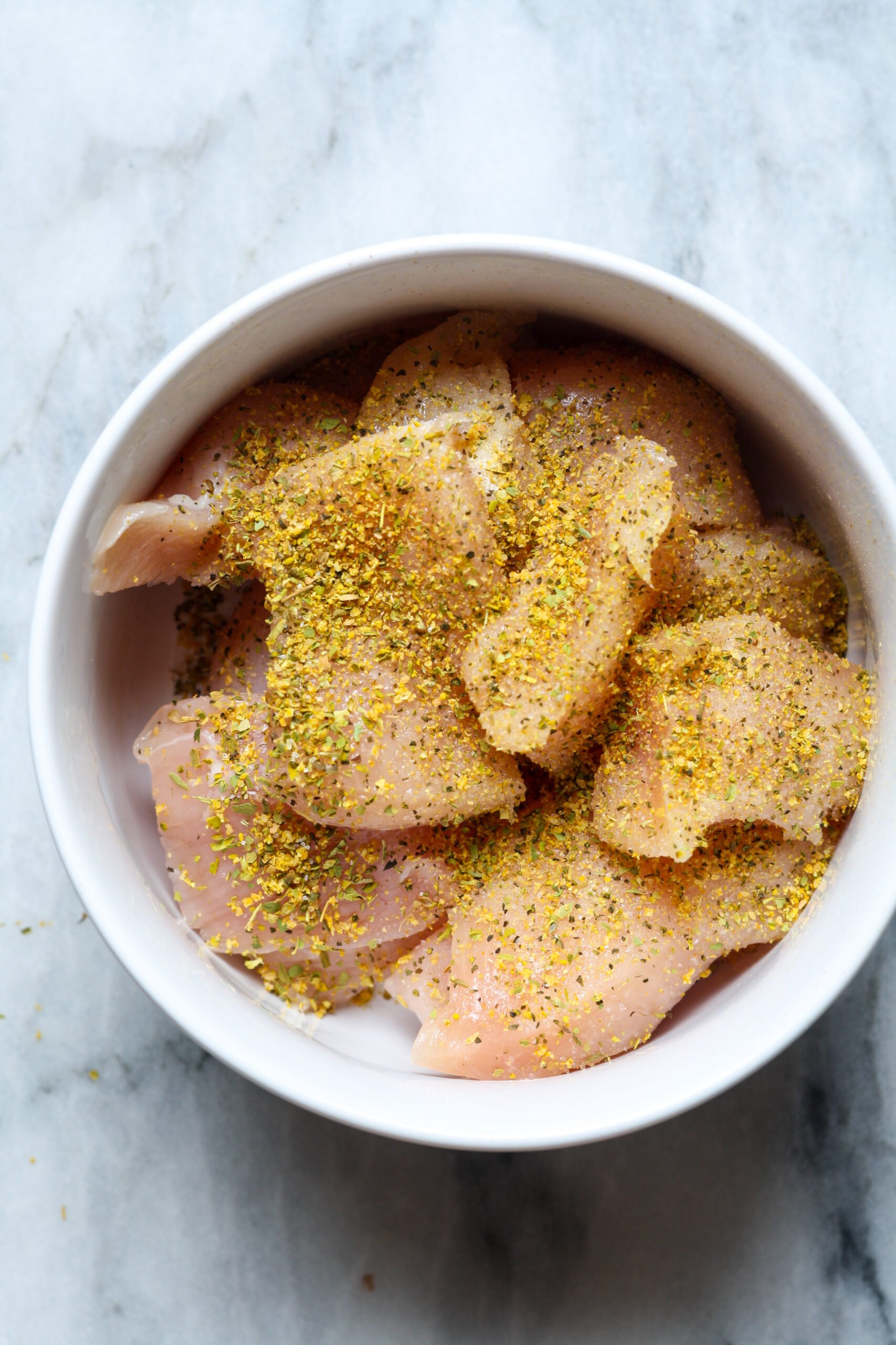 Seasoned chicken breast in ramekin.